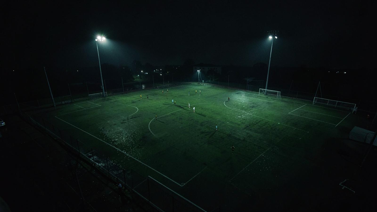 Floodlit soccer pitch shot from a tactical camera angle at night